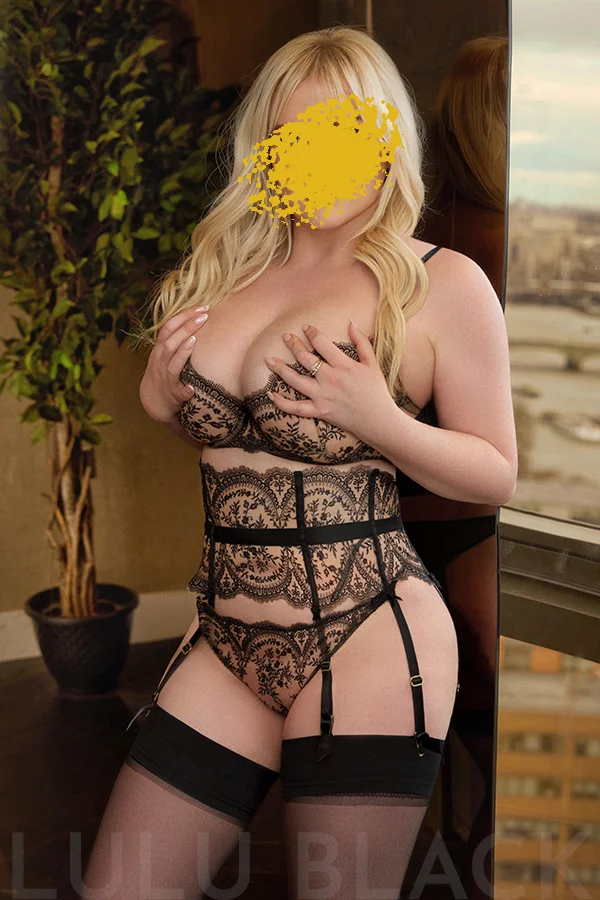 Beautiful blonde Amber looking fabulous in high end black lingerie including a waspie and suspenders.