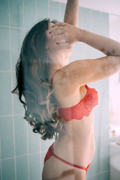 A picture in red, Nina looking tempting in a two piece underwear set, hand in her long brown hair.